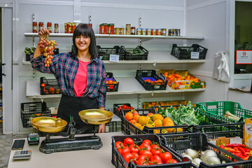 Portrait of shopkeeper in the greengrocer, showing a bunch of tasty grapes.