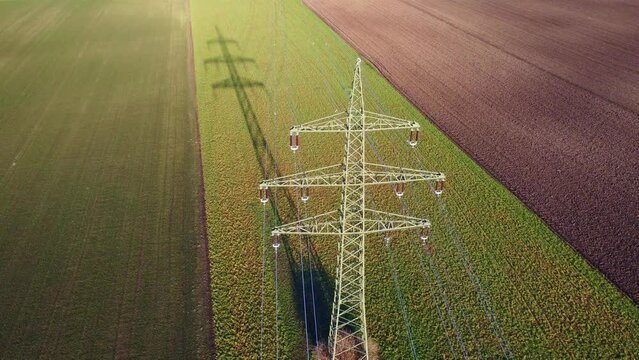 Power supply pole on farmland with powerlines and cables