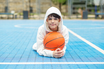 Teen athlete with basketball on background of blue sports court. Sport and hobby concept. White...
