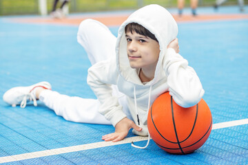 Close up. Teen athlete with basketball on background of blue sports court. Sport and hobby concept....