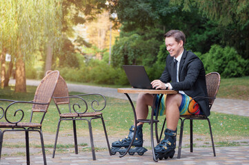 Work and relax.  smiling Businessman dressed in suit, shorts and rollers working with laptop at the...