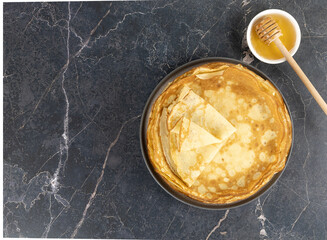 French crepes, pancakes or Russian bliny with honey on a gray background. Top view. Copy space.