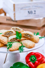 Typical Argentinean food. Meat Empanadas. White wood background. Vegetables around.  Close-up.