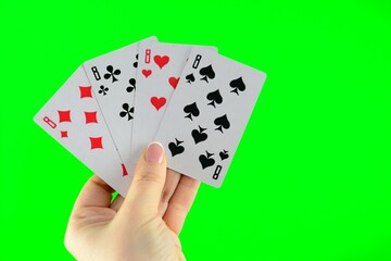 Hand holding four eights on a green background close-up High quality photo