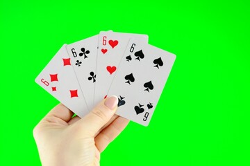 Hand holding four sixes on a green background close-up High quality photo