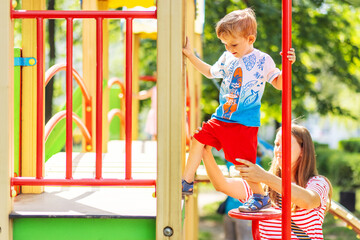 A boy having fun while playing on the playground in the daytime in summer