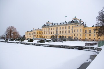 Fototapeta na wymiar View of Drottningholm Palace from the gardens in winter. It is the residence of the Swedish royal family and is located near the capital Stockholm, Sweden. The park is covered in snow.