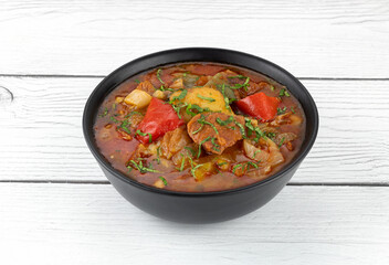 Khashlama stew of beef or lamb meat with vegetables on a black plate, top view. Armenian and Georgian cuisine.