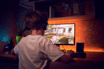 Boy playing shooter online video game - Technology trend concept - Main focus on headphones