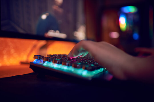 Hands Of Gamer Man Playing Video Games On Computer In Dark Room Using Backlit Colorful Keyboard