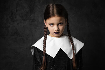 A sullen girl with pigtails in a black dress with a white collar
