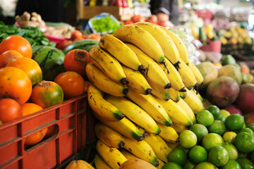 bunch of bananas in the foreground in the middle of a fruit and vegetable market