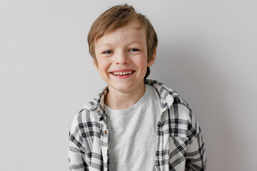 Happy little boy smiling to the camera. Grey studio background.