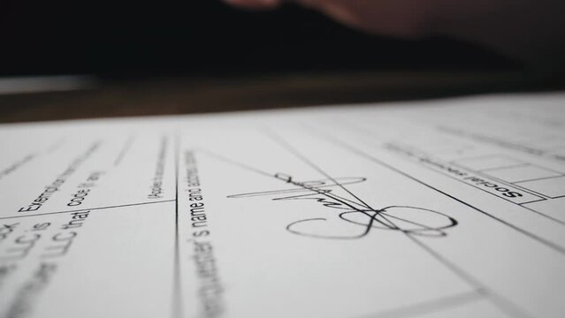 Close-up of hand of unrecognizable person signing a document by ballpoint pen, concluding contract