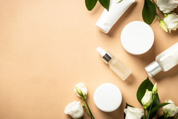 Natural cosmetic products at color background. Cream, serum, tonic with green leaves and flowers. Flat lay image with copy space.