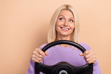 Portrait of nice woman with straight hairdo wear violet sweater look empty space hold steering wheel isolated on beige color background