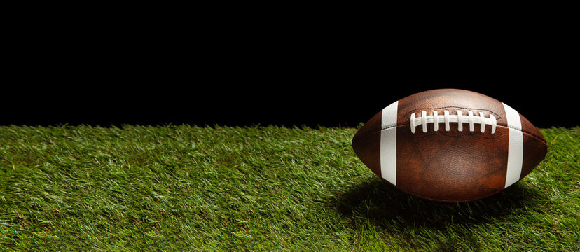 American football ball on green grass field. Banner with space for text.