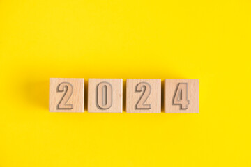 Wooden cubes with numbers 2024 yellow background.