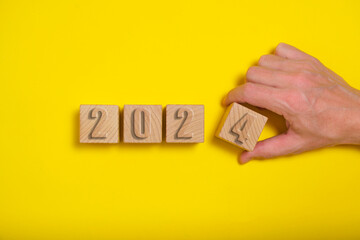 Wooden cubes with numbers 2024 yellow background are made by hand.