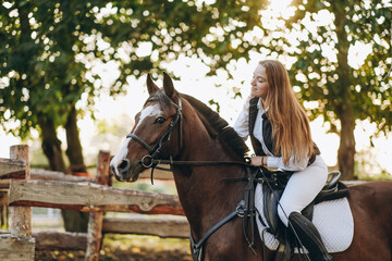 A young female jockey is sitting on her horse in show jumping training. Preparing for the...