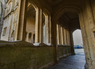 Obraz premium Medieval stone arch walkway. Historical Flagstone flooring leads the way. Contrasting shadows cast beneath the aches. Copy space