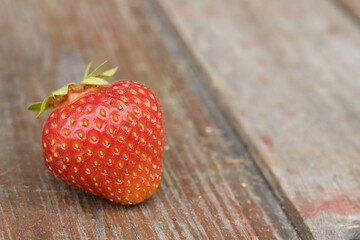 Macro view of strawberry on the wooden background. Gardening concept.