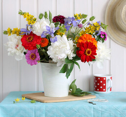 summer rustic still life with a bouquet of garden flowers. peonies, zinnias, irises and carnations.