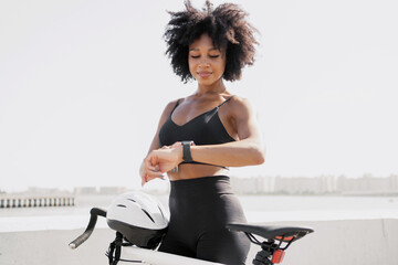 A female cyclist looks at a fitness watch, measures the number of calories after a workout.