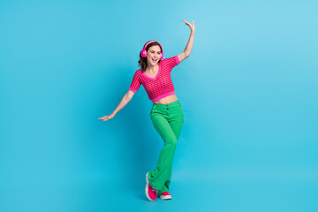 Fototapeta na wymiar Full length photo of carefree lovely girl with curly hairdo dressed pink top dancing look empty space isolated on blue color background