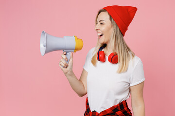 Young surprised shocked excited fun woman wearing white t-shirt red hat hold in hand megaphone...