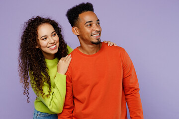 Obraz premium Young minded couple two friends family man woman of African American ethnicity wear casual clothes together look aside on workspace area mock up hug isolated on pastel plain light purple background.