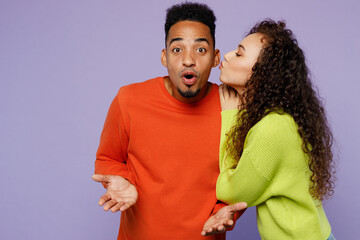 Young couple two friends family man woman of African American ethnicity wear casual clothes together girl kissing guy in shock because he did not expect that isolated on plain light purple background.