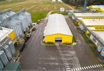 Naklejka premium Modern agro-industrial complex top view. Flying a drone over a large chicken farm, raising broiler chickens for meat. Rows of chicken coops and silver grain silos.