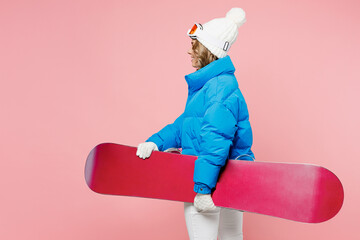 Sideways satisfied snowboarder happy woman wear blue suit goggles mask hat ski padded jacket look camera isolated on plain pastel pink background Winter extreme sport hobby weekend trip relax concept. © ViDi Studio