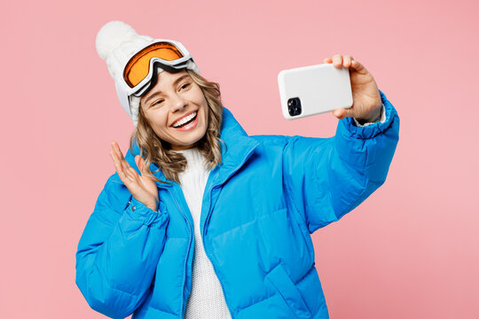 Snowboarder woman wear blue suit goggles mask hat ski padded jacket do selfie shot on mobile cell phone isolated on plain pastel pink background. Winter extreme sport hobby weekend trip relax concept.