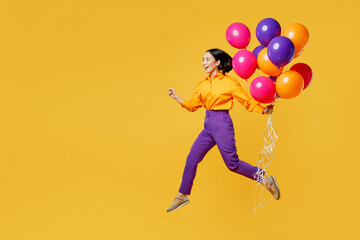 Fototapeta na wymiar Full body side profile view happy fun young woman wear casual clothes celebrating hold bunch of balloons jumping high run fast isolated on plain yellow background. Birthday 8 14 holiday party concept.