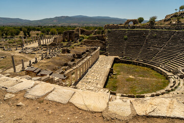 Fototapeta na wymiar Ruins of Roman theater in Aphrodisias old greek city in Geyre, Aydin, Turkey. The Tetrastoon and the Imperial Hall (basilica) on the background. 
