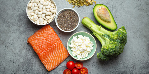 Selection of healthy food products if a person have diabetes: salmon fish, broccoli, avocado, beans, vegetables, seeds on grey background from above. Healthy diabetes diet