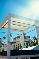 Beach lounge vacation and summer view of some beds in a beach club in a white sand beach in Tenerife. Beach beds among palm trees at perfect tropical coast.