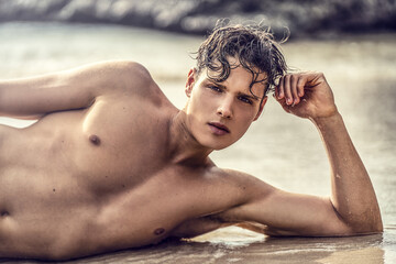 Portrait of handsome young italian man relaxing at the tropical beach, lying and looking at the...