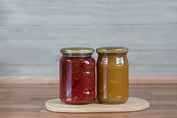 Strawberry jam and apricot jam in glass jars on a wooden surface. Banner. Copy space
