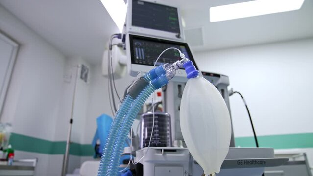 Contemporary lung ventilation system working in modern surgical room. Ambu bag inflating at foreground.