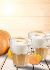 Tasty coffee with foam  and pumpkin on the desk