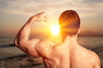 Young sporty strong sportsman train on beach background