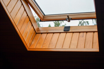 Detail of partially opened skylight window installed into roof of the wooden log house