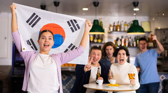 Group of happy friends with flag of South Korea celebrating victory of their favorite team in a beer bar