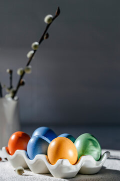 Painted colorful Easter eggs in a stand, a vase with a willow branch