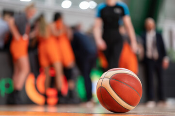 the ball lying on the parquet and the basketball team in the background.