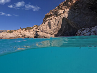 Fototapeta na wymiar Underwater split photo of famous paradise turquoise pebble beach of Seychelles in island of Ikaria, Aegean sea, Greece