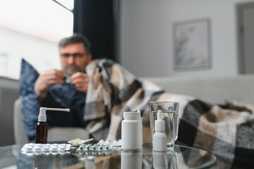 Portrait of sick senior man with thermometer posing at home